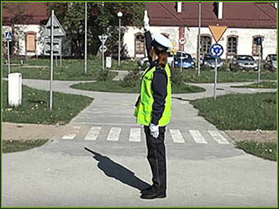 policjantka stoi bokiem z podniesioną ręką