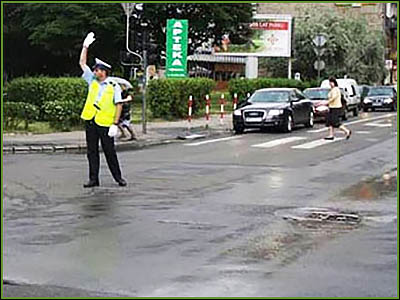 policjant stojący przodem z podniesioną ręką